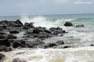 Rocks to the left of the sandy shoreline.